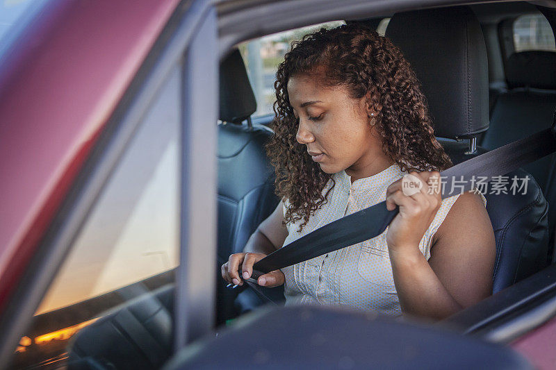 黑人妇女系上安全带驾驶汽车。