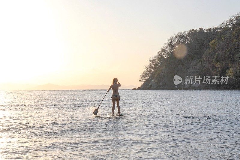 日出时，年轻女子在太平洋上划桨