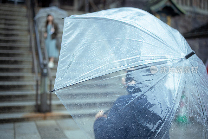 年轻女子在雨天拍她的朋友