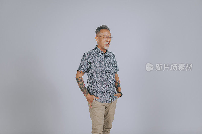 亚洲华人老年男子灰色头发与头发胡茬手在口袋微笑幸福灰色背景