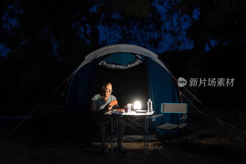 一个老人在露营的时候一边放松一边用手机
