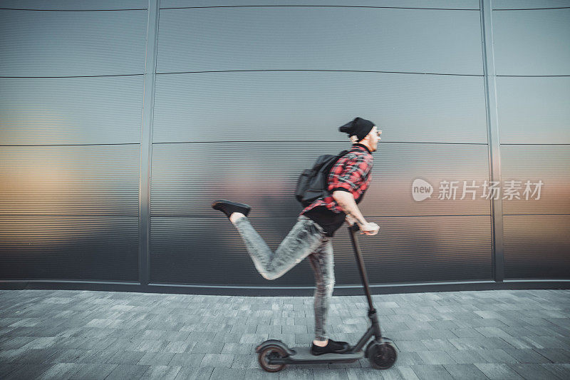 一个年轻人骑着他的电动摩托车。技术、生态的移动性概念。一个骑着电动踏板车的潮人。