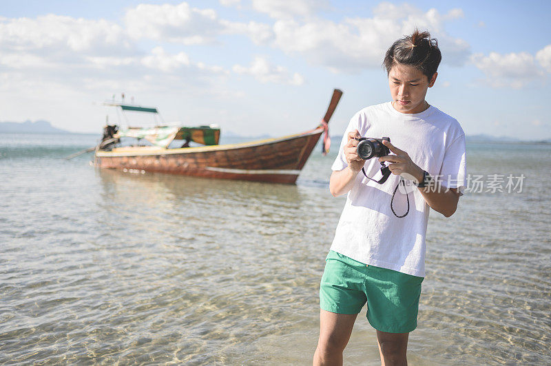 在泰国普吉岛热带海岸线拍下美丽的日落后，亚洲男人从海上走出来