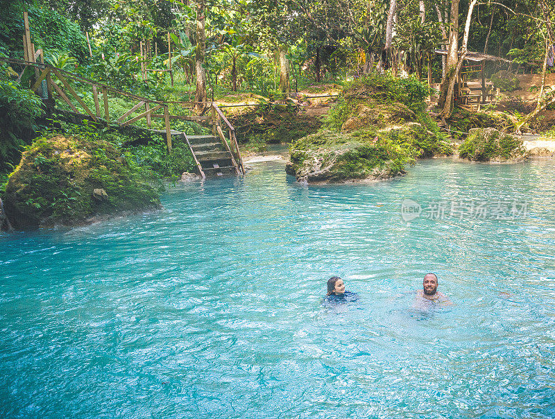 家庭游泳在与世隔绝的自然瀑布泻湖在热带天堂