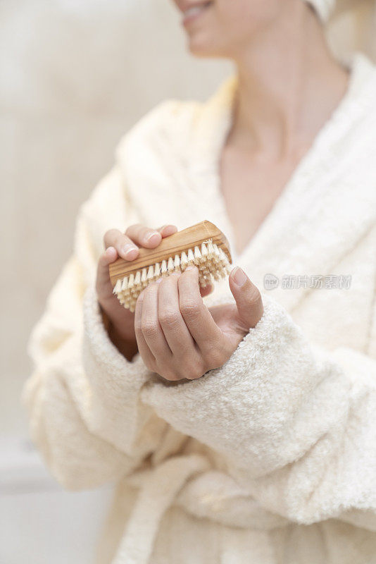 年轻漂亮的女人洗完澡用指甲刷照顾自己的手