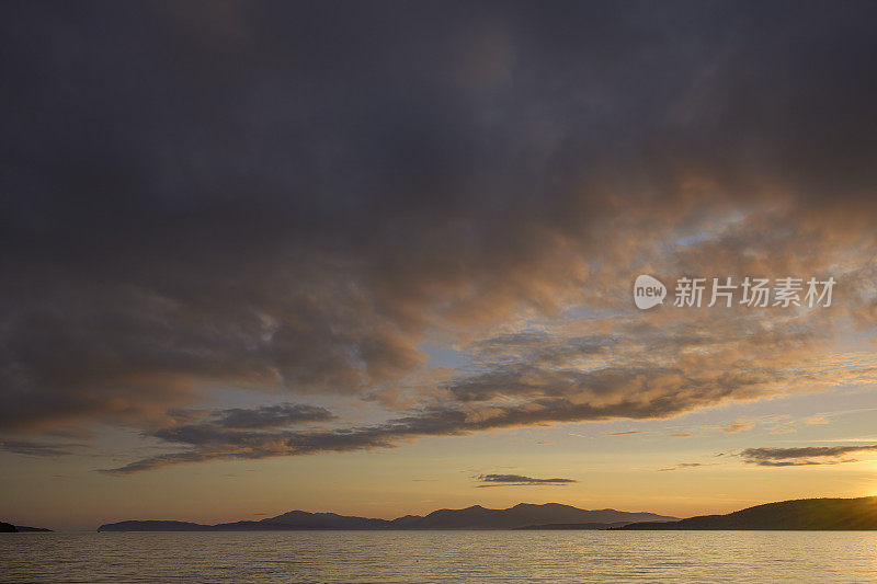 从苏格兰阿吉尔郡北莱迪格海滩俯瞰阿德穆克尼什湾的日落全景。