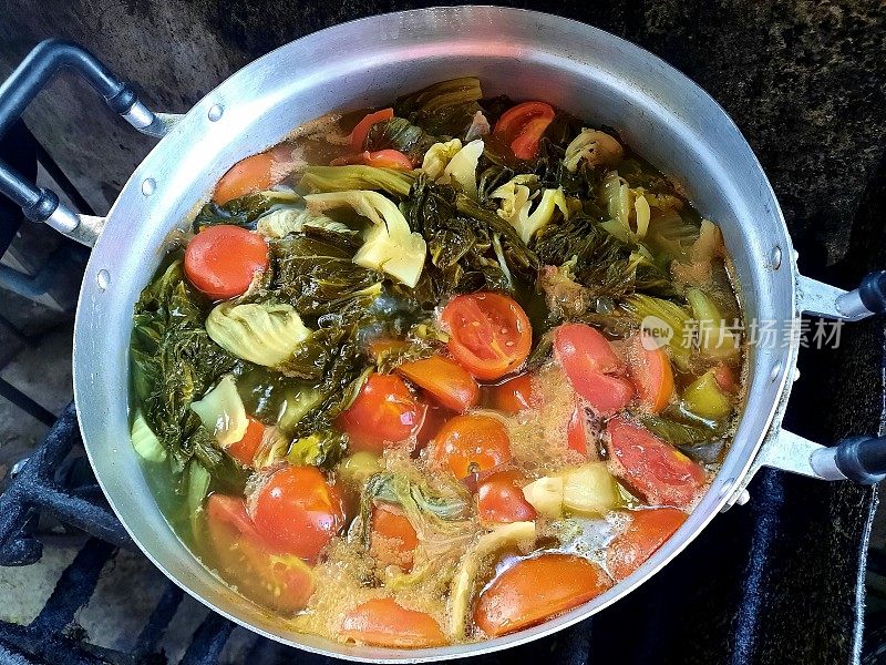 煮腌莴苣和番茄汤与猪肉裂口在炉灶食品准备。