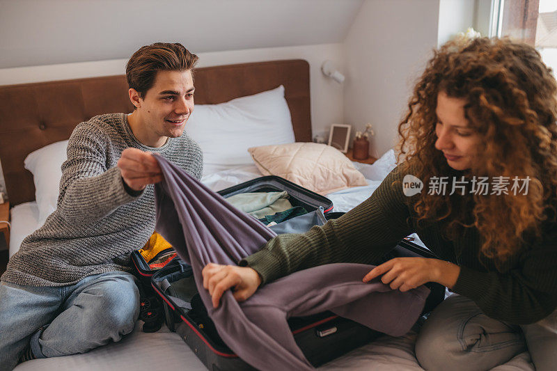 一对年轻夫妇在旅馆的卧室里一起打开行李。