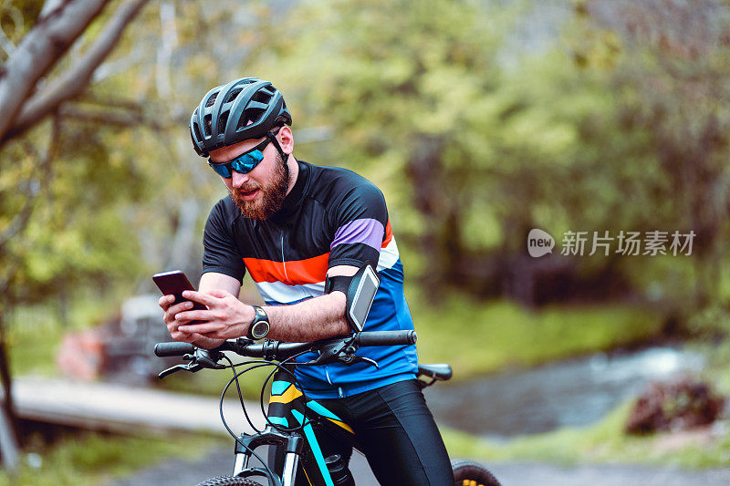 现代男性自行车手编程智能手机，在自然中骑行的新路线