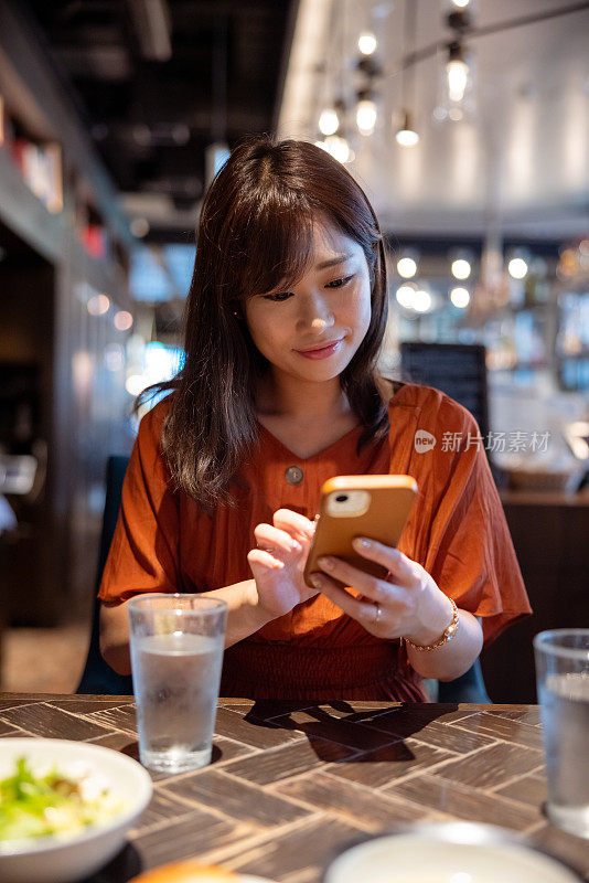 女性自由职业者，午餐前在餐厅使用智能手机