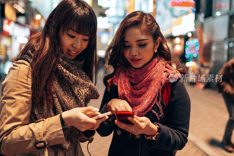 朋友们在东京街头查看社交媒体