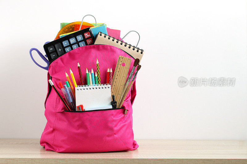 粉色书包上有白色的学习用品。