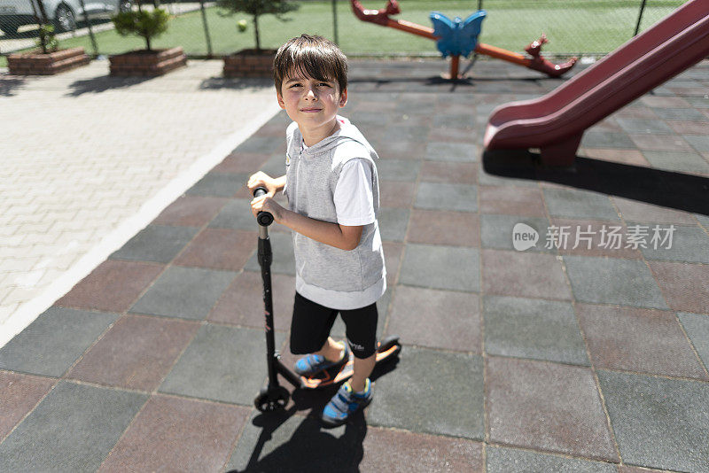 一名小学生在自家操场上骑着滑板车。