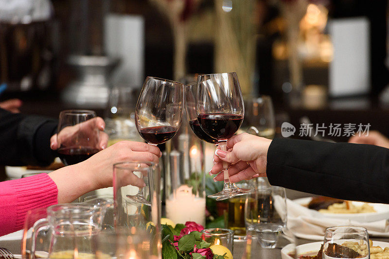 人们手里拿着盛有红酒的玻璃杯。婚礼。朋友们在餐桌上举杯祝酒