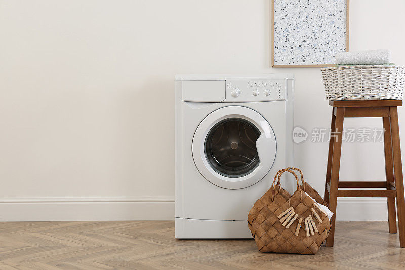 洗衣房内部有现代化的洗衣机和靠近白墙的木凳。文本空间