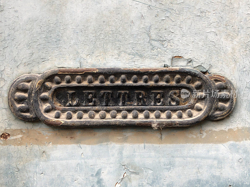 法国:破旧灰墙上锈迹斑斑的旧字母槽