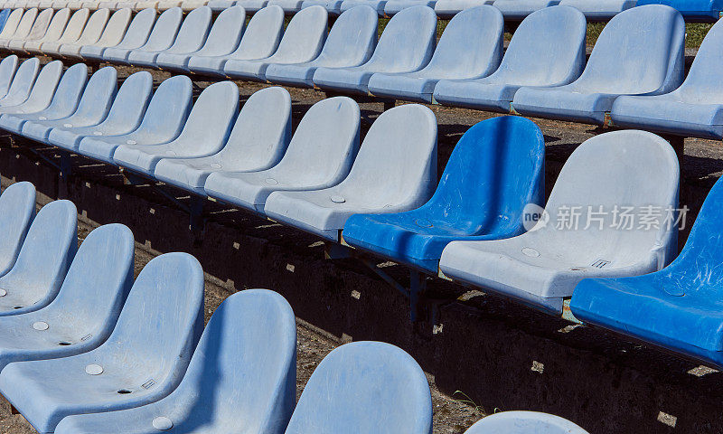 成排的体育场看台座位。生锈的蓝白塑料体育场座椅。旧体育场里的蓝色椅子。