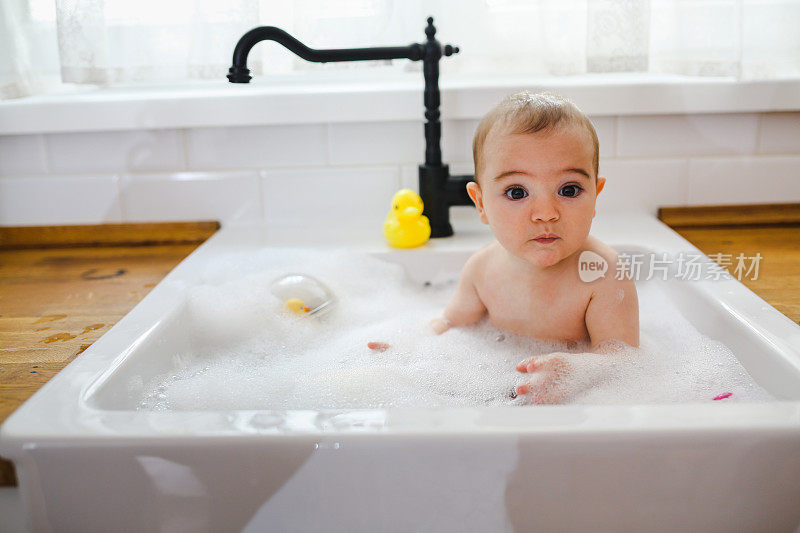 婴儿在厨房水槽里洗澡