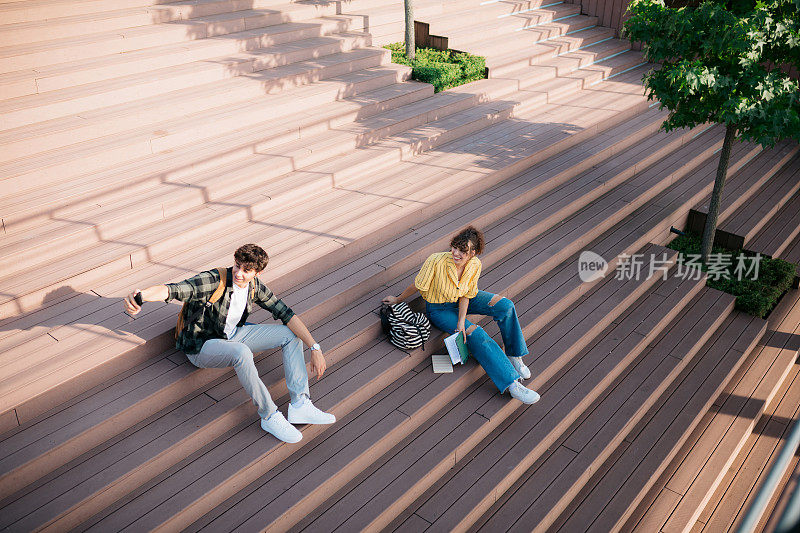 男学生和朋友坐在城市外面的台阶上自拍