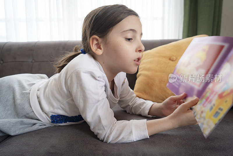 小女孩正在家里读一本儿童读物