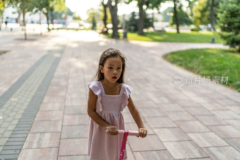小女孩骑着滑板车