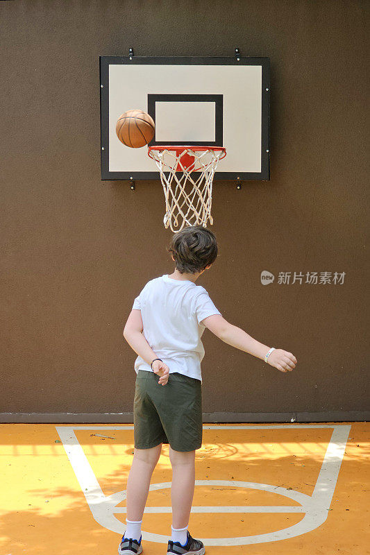 8岁的孩子把球扔向篮筐