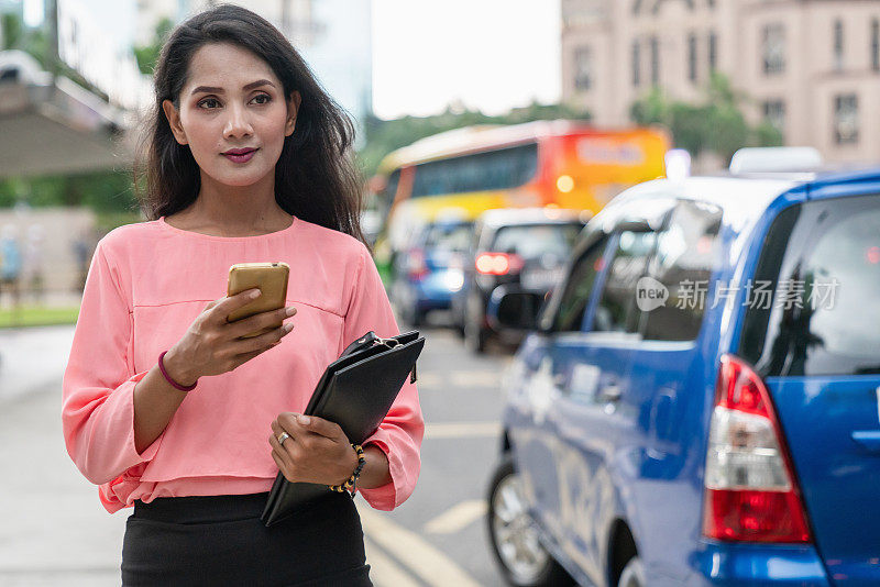 吉隆坡市区街道上使用手机的妇女