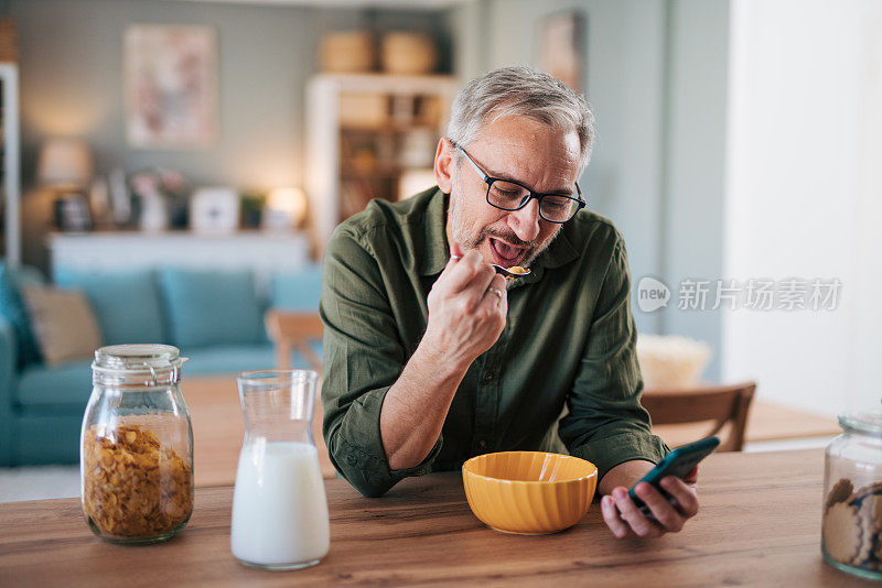 快乐的老人边吃早餐边看网上报纸