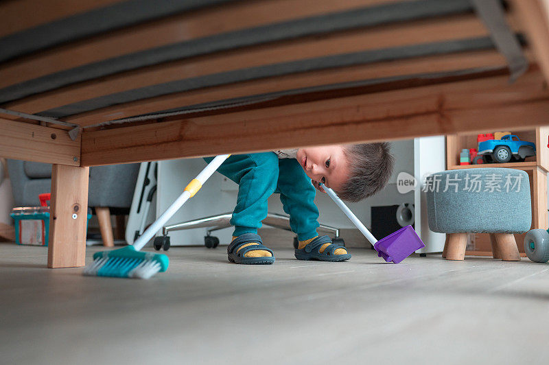 两岁半的小男孩高兴地在家里的床下扫地玩家务活动
