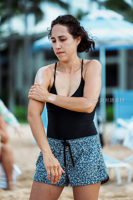 一名女子在海滩上涂抹防晒霜