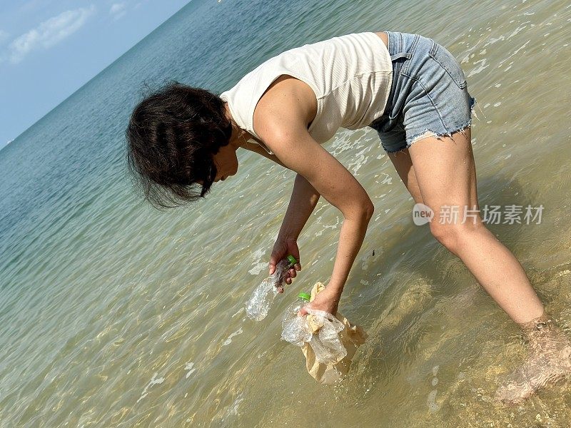 妇女从海里捡塑料垃圾特写