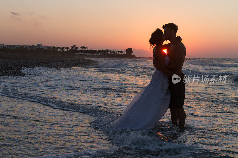 黄昏时分，一对新婚夫妇在朦胧的海滩上