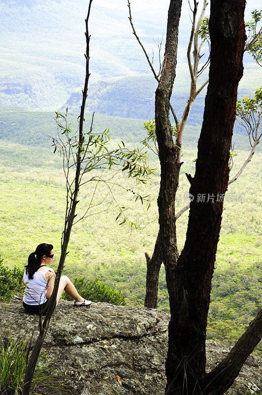 徒步女坐在看风景照片从背后