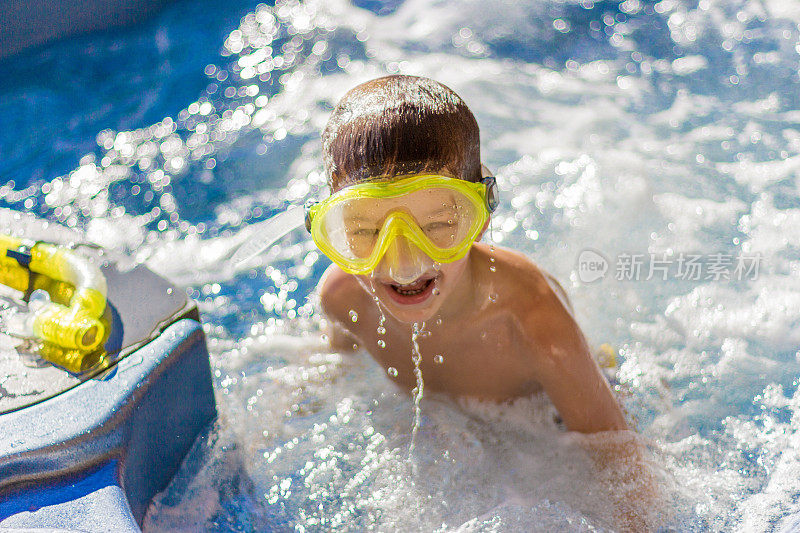 可爱的男孩戴着游泳面具在游泳池里玩