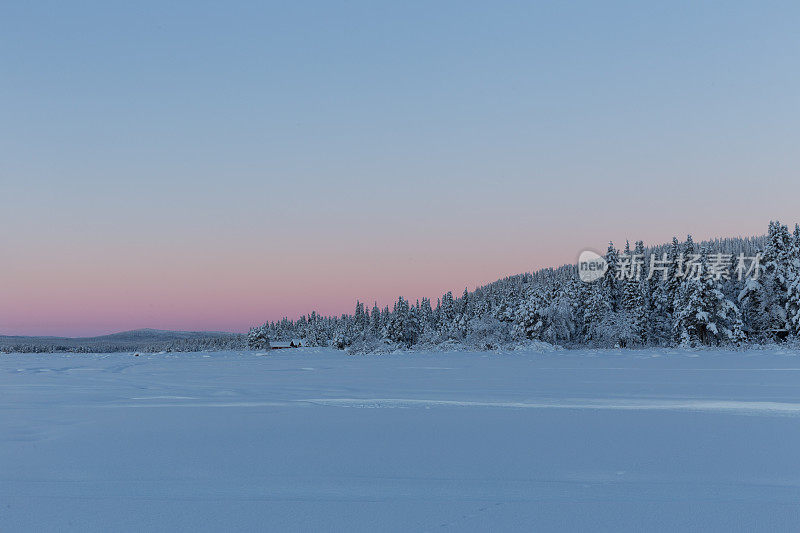 瑞典北极地区冬天的积雪覆盖了树木和结冰的湖泊