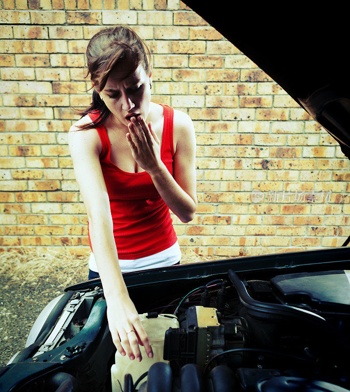 震惊年轻的褐发女人看发动机的故障汽车