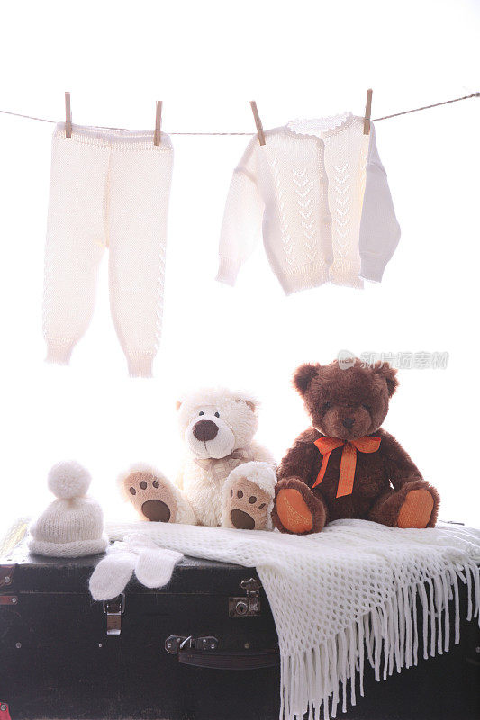 两个朋友坐着泰迪熊，盖着箱子，挂着婴儿衣服