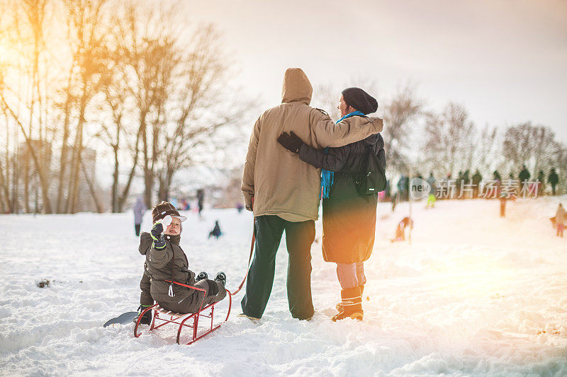 快乐的男孩和他的家人在雪地上