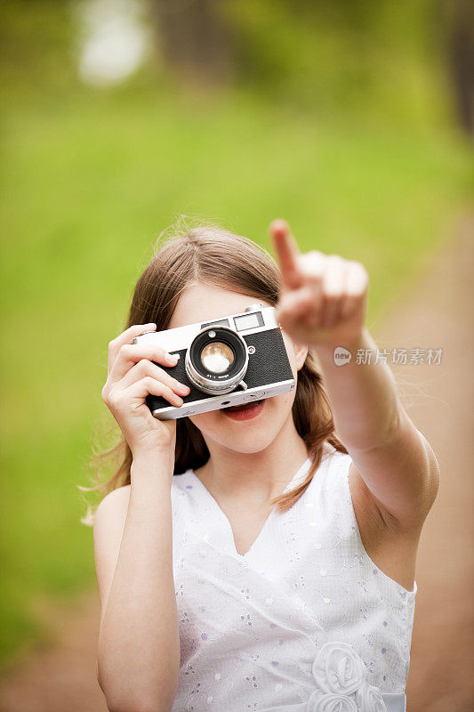 小女孩指着古董相机拍照