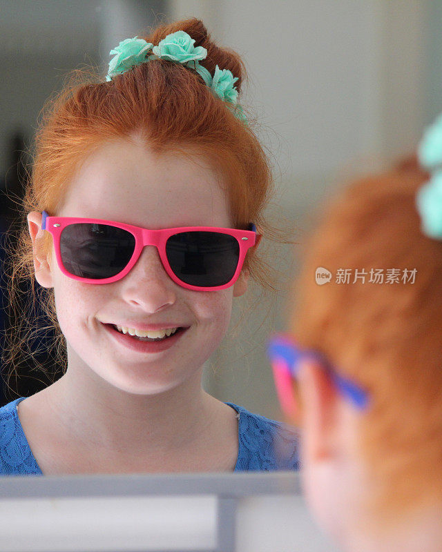 红发髻的女孩，看着镜子，戴着墨镜