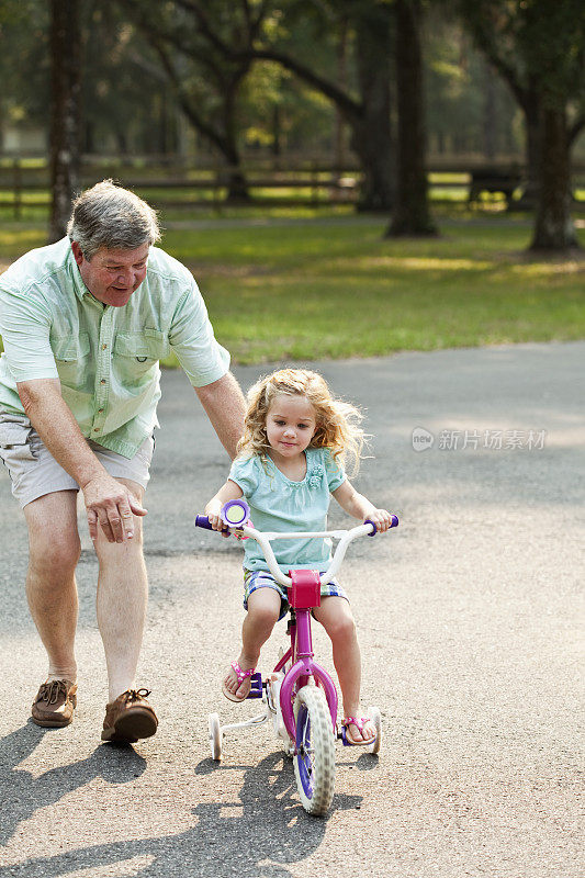 小女孩和爷爷一起骑自行车