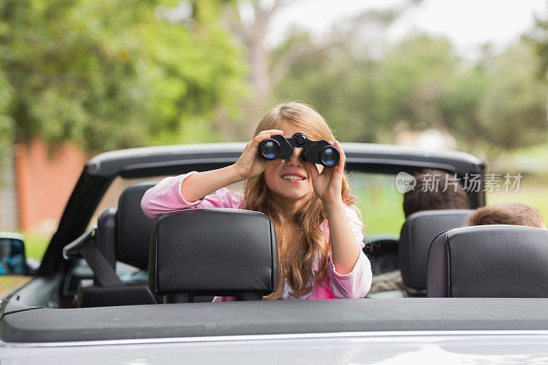 可爱的小女孩用双筒望远镜从后座往外看