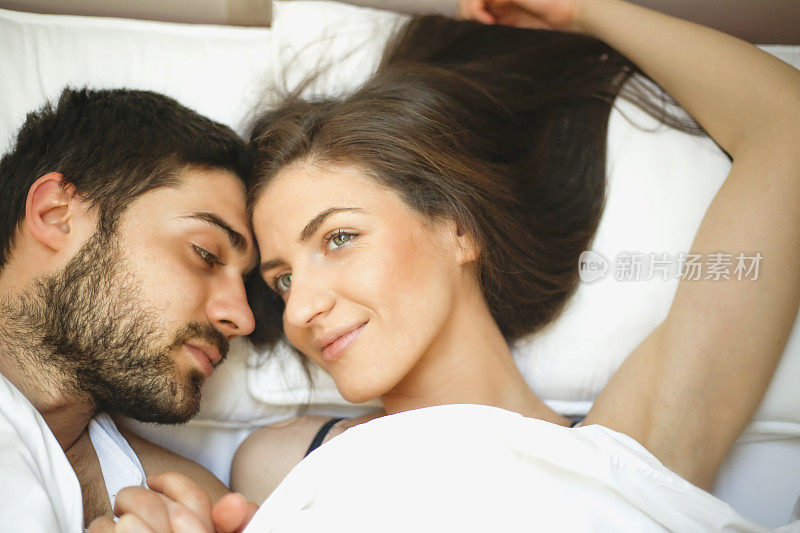 一对年轻夫妇在卧室的床上拥抱