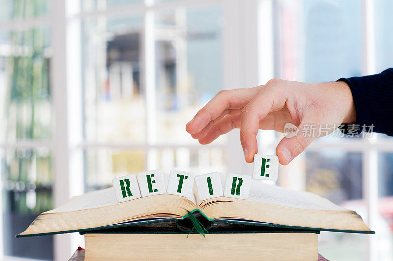 退休概念，手与字母块