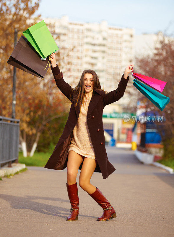 快乐的女人拿着购物袋，蹦蹦跳跳