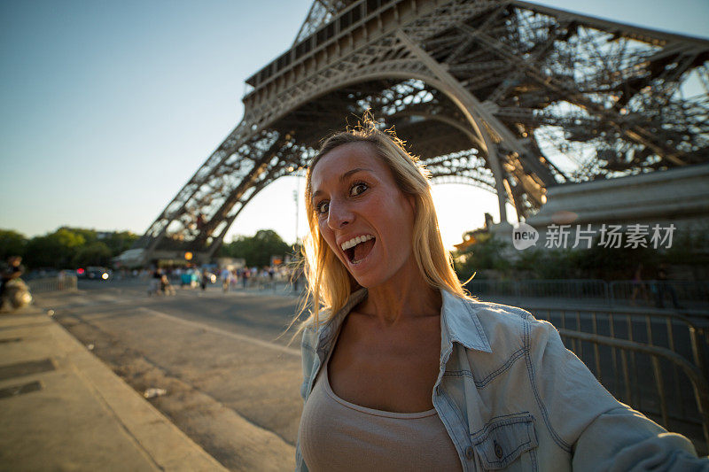一名兴高采烈的年轻女子在巴黎埃菲尔铁塔自拍