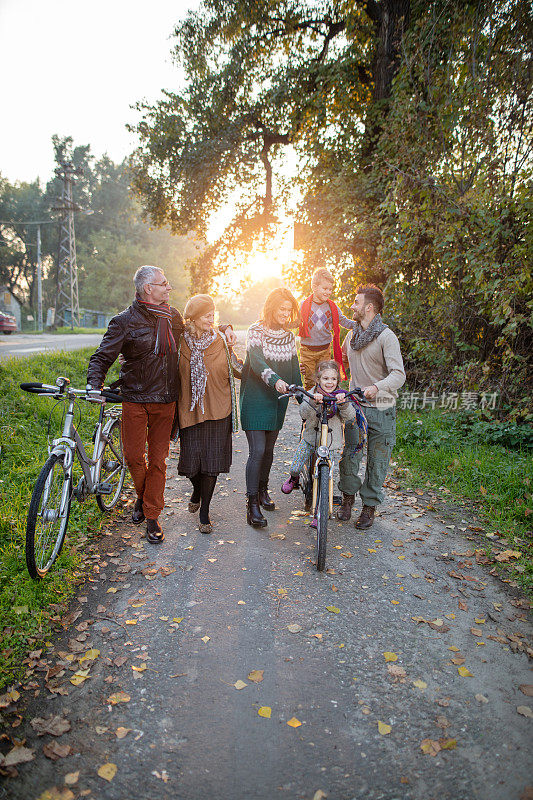 几代同堂的一家人在公园里骑着自行车散步。