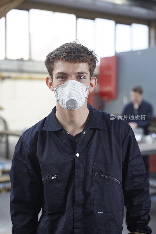 在钢铁制造厂戴口罩的年轻学徒