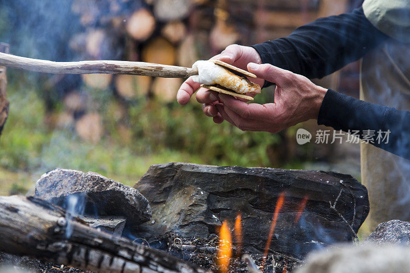 手在篝火上用棉花糖和巧克力做Smores