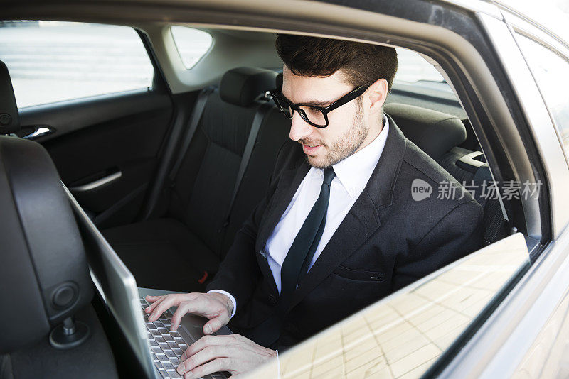 一个商人在车里用笔记本电脑工作
